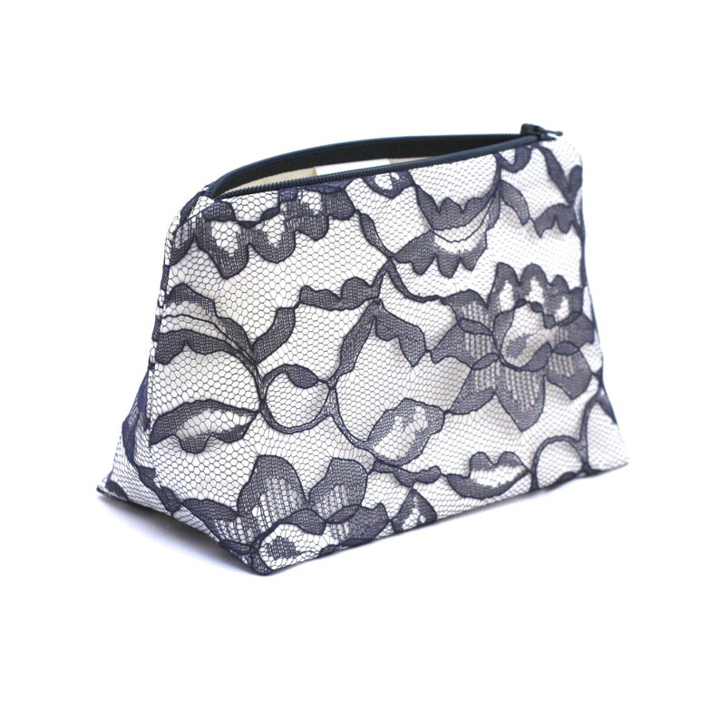 May include: A white and black lace cosmetic bag with a zipper closure.