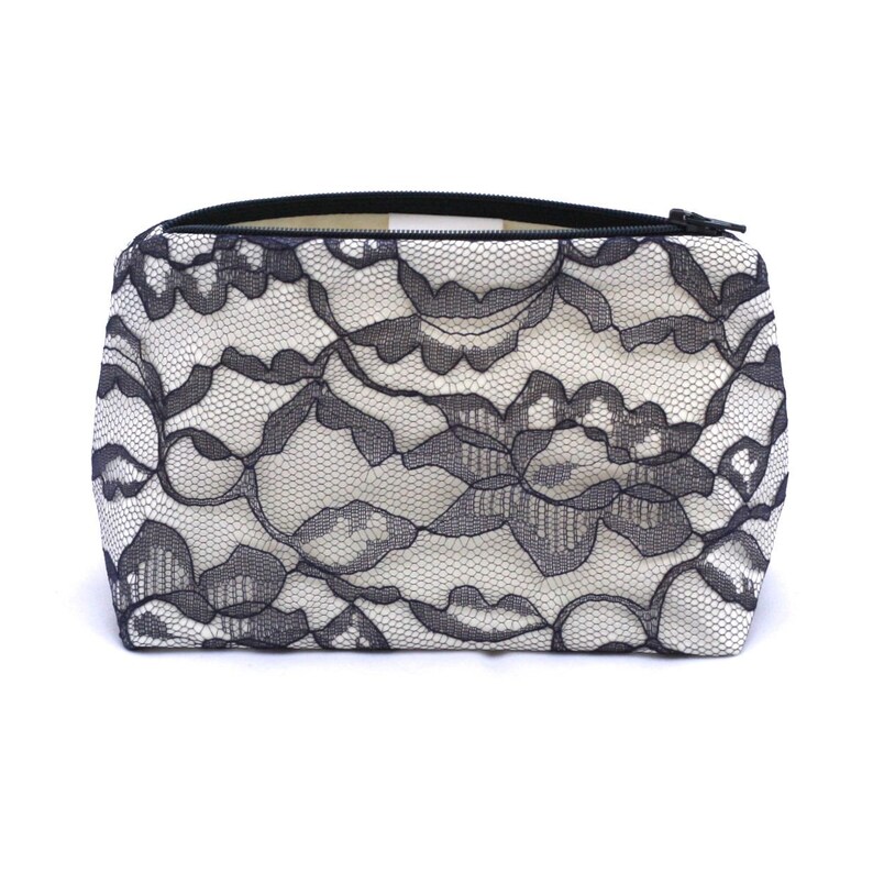 May include: A white zippered pouch with a black lace pattern.
