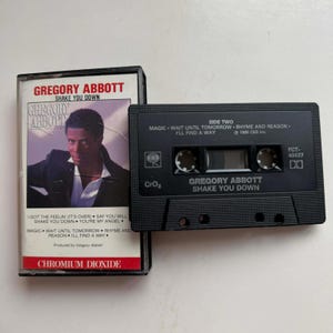 Könnte beinhalten: Eine Vintage-Kassette und Hülle für Gregory Abbotts Album "Shake You Down". Die schwarze Kassette hat weißen Text, und die Hülle zeigt ein Foto des Künstlers. Der Albumtitel und der Name des Künstlers sind deutlich sichtbar.