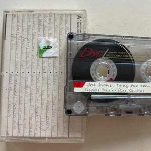 May include: A clear cassette tape labeled "D90" with the text "JOE DIFFIE - THIRD ROCK FROM GEORGE STRAIT - PURE COUNTRY." The cassette case has handwritten song titles. The tape is a vintage music format.