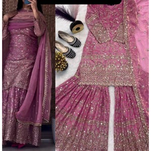 Puede incluir: Un conjunto salwar kameez magenta adornado. El conjunto incluye una parte superior de manga larga, pantalones de pernera ancha y una bufanda a juego. El atuendo está ricamente decorado con bordados y lentejuelas doradas. La imagen también muestra un par de zapatos adornados en blanco y negro.