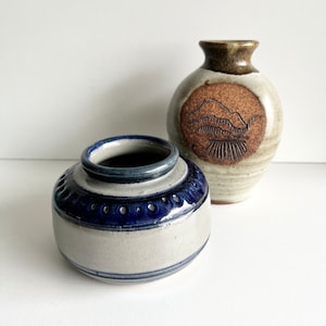 Peut inclure: Deux vases en céramique, l'un avec un motif bleu et blanc et l'autre avec un motif brun et blanc représentant une scène de montagne.