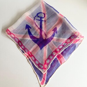 May include: A white silk scarf with a pink and blue anchor design. The anchor is surrounded by a chain link border.