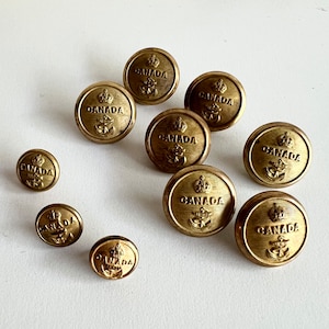 May include: Ten gold-coloured metal buttons with the word "CANADA" embossed on each. The buttons have a crown and an anchor design.