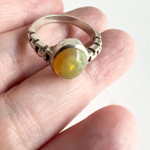 May include: A silver ring with a yellow opal gemstone. The ring has a textured band.