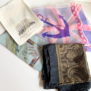 May include: Four different silk scarves. One features a Union Jack with a purple anchor, another has a paisley pattern, a third has a scene of a changing of the guard, and the last has a tartan pattern with the text "The Kile of Bute".