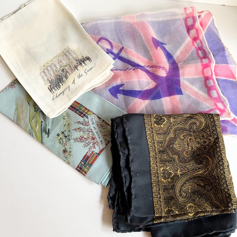 May include: Four different silk scarves. One features a Union Jack with a purple anchor, another has a paisley pattern, a third has a scene of a changing of the guard, and the last has a tartan pattern with the text "The Kile of Bute".