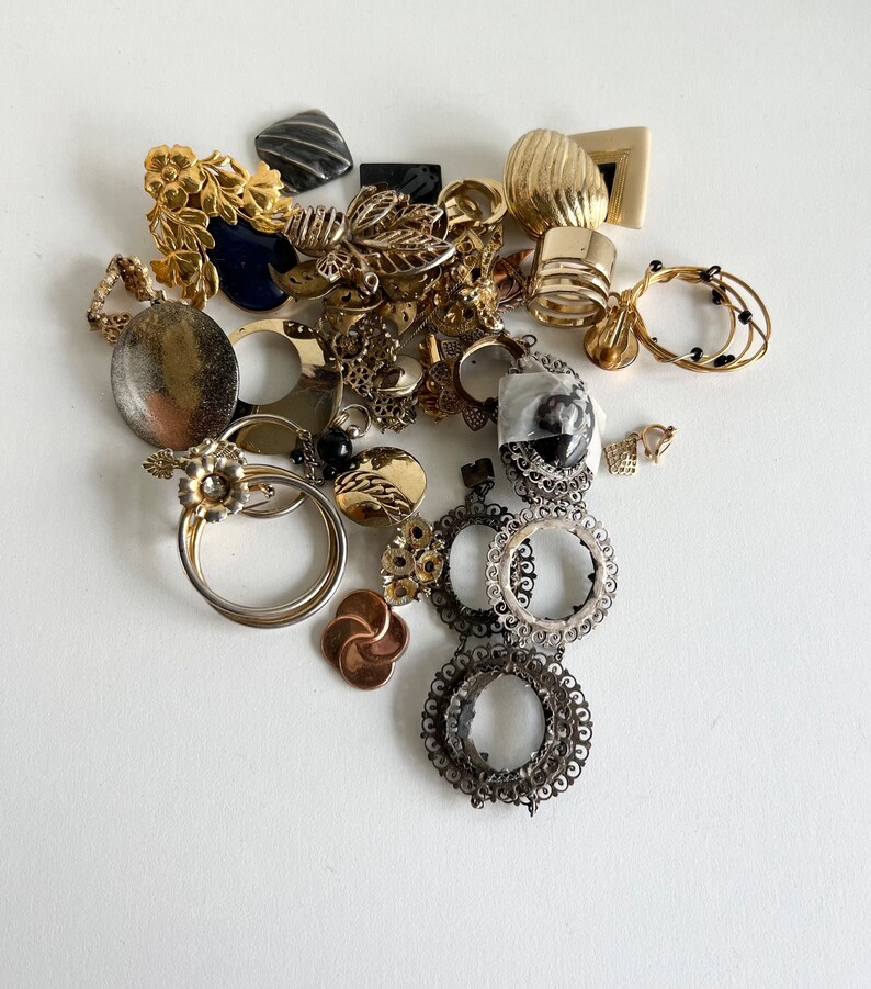 Puede incluir: Una colecci&oacute;n de pendientes vintage de oro y plata, que incluye un par de pendientes grandes de aro con dise&ntilde;os intrincados, un par de pendientes de aro m&aacute;s peque&ntilde;os con cuentas negras y un par de pendientes colgantes con un dise&ntilde;o floral.