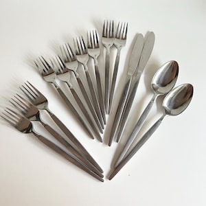 May include: A set of cutlery, including forks, spoons, and a knife, all made of stainless steel. The cutlery is arranged in a fan shape on a white surface.