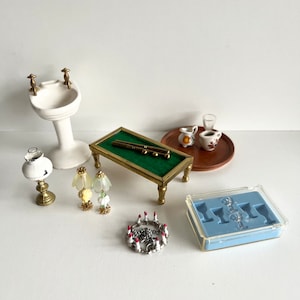 May include: A miniature dollhouse set with a white porcelain sink, a green felt pool table, two lamps, a silver crown, and a clear plastic tray with miniature glasses.