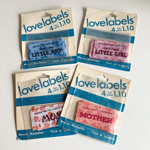 May include: Four packs of woven iron-on labels with different designs. The labels are white with blue, pink, and red floral patterns. The text on the labels reads "Hand Made For My Special Little Boy", "Hand Made For My Special Little Girl", "Made With Love Mom", and "Made With Love By Mother".