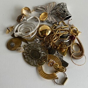 Puede incluir: Una colecci&oacute;n de joyas de oro y plata, que incluye pendientes, colgantes y un dije de mariposa. Las joyas est&aacute;n dispuestas sobre una superficie blanca.