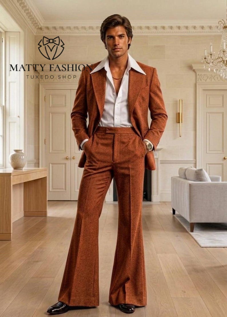 May include: A rust-colored suit with wide-leg pants and a white collared shirt. The suit jacket has a two-button closure. The image includes the text "MATTY FASHION TUXEDO SHOP". The man is wearing a gold chain and a watch.