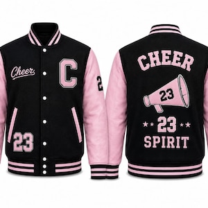 May include: A black and light pink varsity jacket featuring a snap-button front, striped ribbed collar, cuffs, and hem. The front displays a letter C, the word Cheer, and the number 23. The back features a megaphone graphic with the text Cheer 23 Spirit.