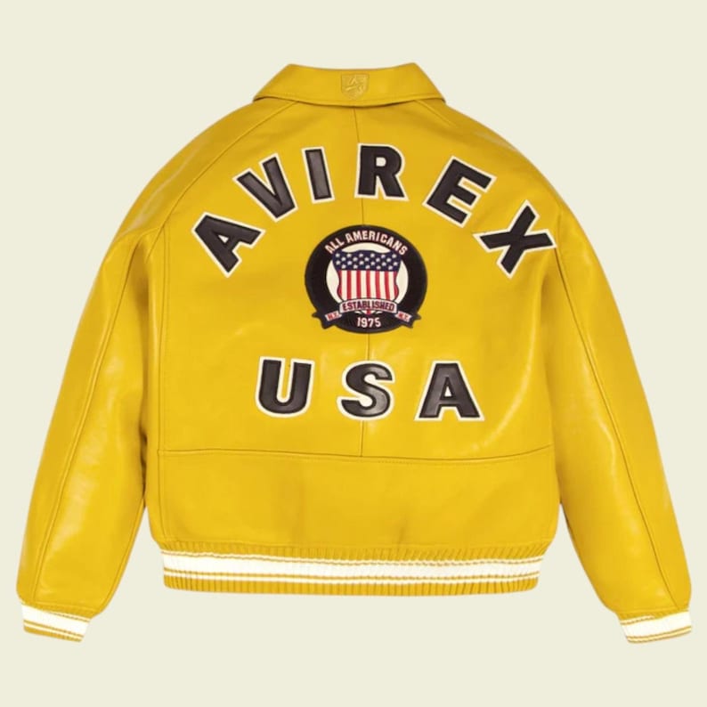 May include: A yellow leather jacket with the word "AVIREX" arched across the back in black letters. Below the word "AVIREX" is a circular patch with the words "ALL AMERICANS" and "ESTABLISHED 1975" surrounding a design of the American flag. The word "USA" is below the patch.