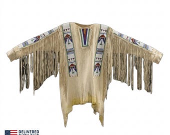 May include: A beige long-sleeve shirt featuring extensive fringe detailing along the sleeves and torso. The garment is decorated with vertical bands of intricate beadwork in white, blue, red, and green patterns across the chest and sleeves.