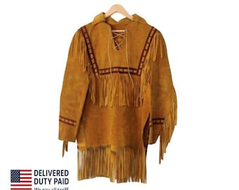 Puede incluir: Una camisa tipo suéter de ante color tostado con largos flecos en el pecho, las mangas y el dobladillo. La prenda incluye un cuello con cordones y adornos decorativos de color marrón oscuro en el pecho y las mangas.