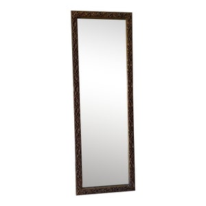 May include: A tall, rectangular mirror with a decorative, ornate, dark brown frame. The frame has a carved, intricate design.