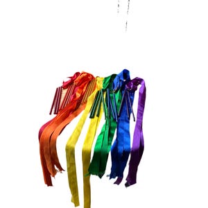 May include: A set of rainbow colored ribbons hanging from a ceiling. The ribbons are tied together at the top and are flowing down in a cascade.