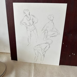 以下が含まれることがあります： 白い紙に鉛筆で描かれた3人の人物の白黒のスケッチ。人物はシンプルでジェスチャーのあるスタイルで描かれている。スケッチは木製の額縁で囲まれている。