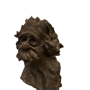May include: A brown ceramic sculpture of a man's head with a textured surface. The sculpture has a detailed face with a long nose, bushy eyebrows, and a beard.