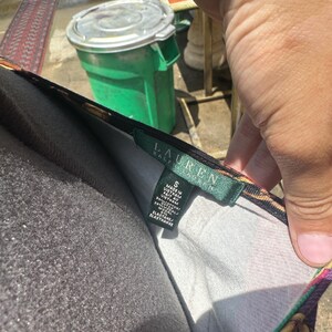 May include: A black and gold patterned dress with a green tag that says "LAUREN RALPH LAUREN" and size "S". The tag also says "Made in Vietnam/Fait au Vietnam" and "RN #73272/CA #20272".