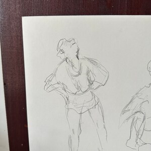 以下が含まれることがあります： 腕組みをして上を見上げる人の鉛筆スケッチ。スケッチはゆったりとしたジェスチャーのスタイルで描かれている。