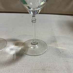 May include: Clear glass martini glass with a long stem and a round base. The glass has a classic, elegant design, ideal for serving cocktails. The stem features a decorative, ridged detail.