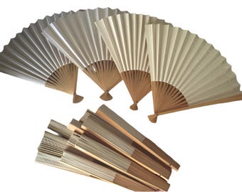 May include: A set of six white paper folding fans with wooden handles. The fans are closed and stacked together.