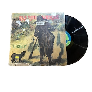May include: A vintage record album cover featuring an illustration of Rip Van Winkle, a man with a gun and a dog, walking through a forest. The album is titled "Rip Van Winkle" and features the text "Read by Ed Begley".