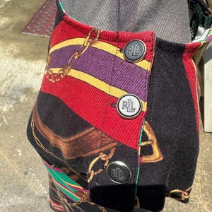 May include: A black and red skirt with a gold chain print and three black buttons with the letters "RL" on them.