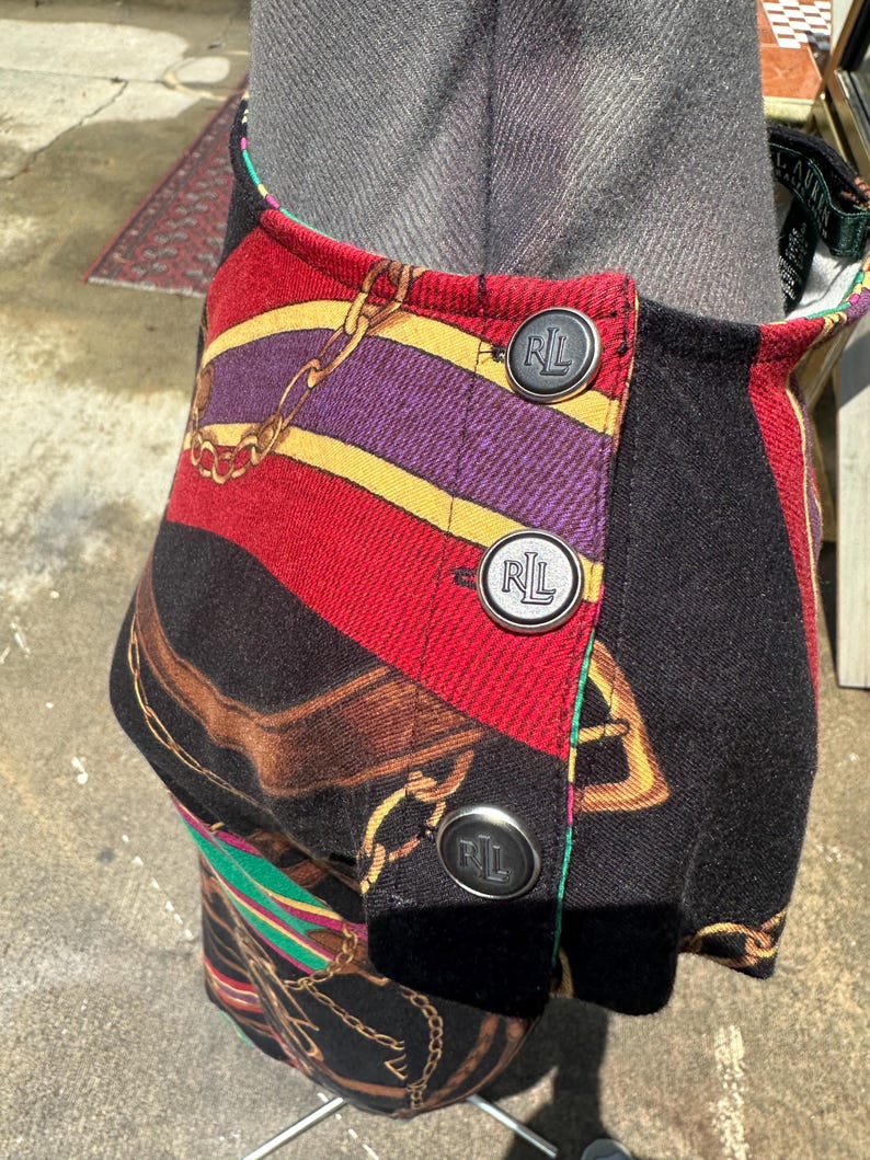 May include: A black and red skirt with a gold chain print and three black buttons with the letters "RL" on them.