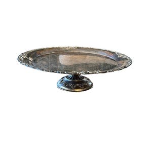 May include: A silver cake stand with a round, scalloped edge and a decorative base.