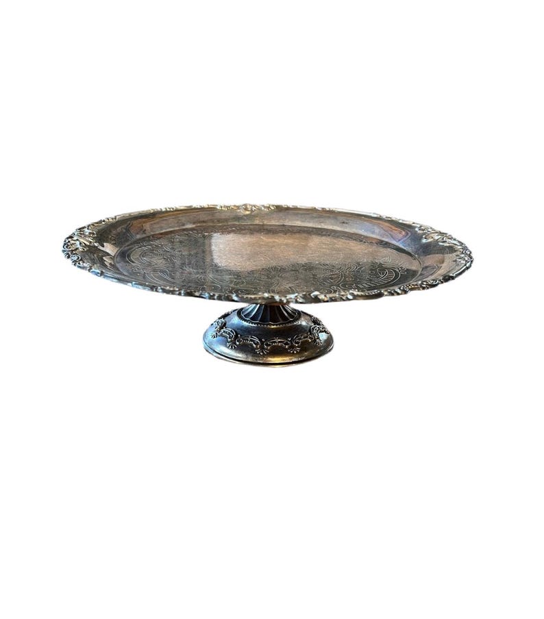 May include: A silver cake stand with a round, scalloped edge and a decorative base.