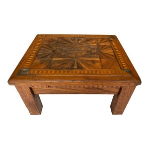 May include: A wooden coffee table with a geometric inlay design on the top. The table has a dark brown finish and four legs.