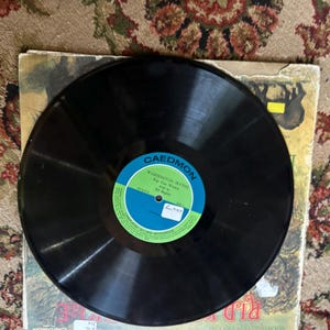 May include: A black vinyl record with a green and blue label that reads "Caedmon" and "Washington Irving Rip Van Winkle Read by Ed Begley".