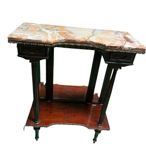 May include: A dark wood console table with a marble top and two drawers. The table has a decorative carved edge and gold accents.