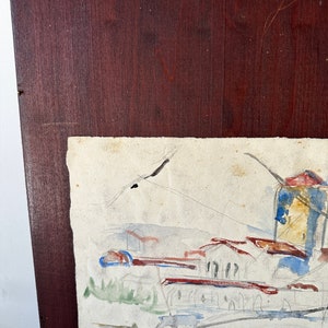 Puede incluir: Una pintura de acuarela de una ciudad con edificios y un cielo en tonos azules, verdes y marrones. La pintura est&aacute; enmarcada en un marco de madera oscura.