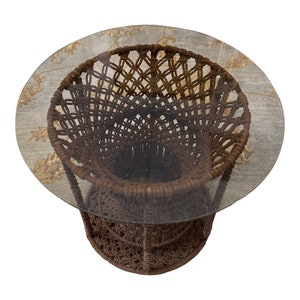May include: A brown macrame coffee table with a round glass top. The table is made of thick rope and has a unique, woven design.