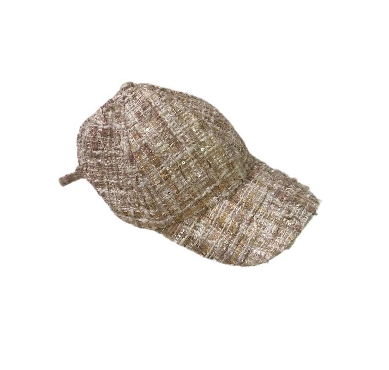 May include: A tweed baseball cap in shades of tan, brown, and gold. The cap features a curved brim and a classic six-panel design. The fabric has a textured appearance with subtle sequin accents, adding a touch of sparkle.