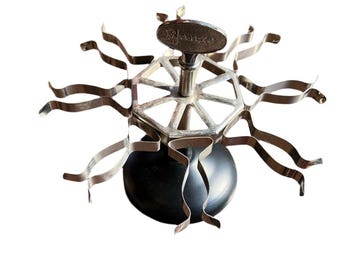 May include: A vintage silver-tone metal stamp holder with a black base. The holder has a circular top with a metal arm that rotates to hold stamps. The arm has a label that reads "Shank's".
