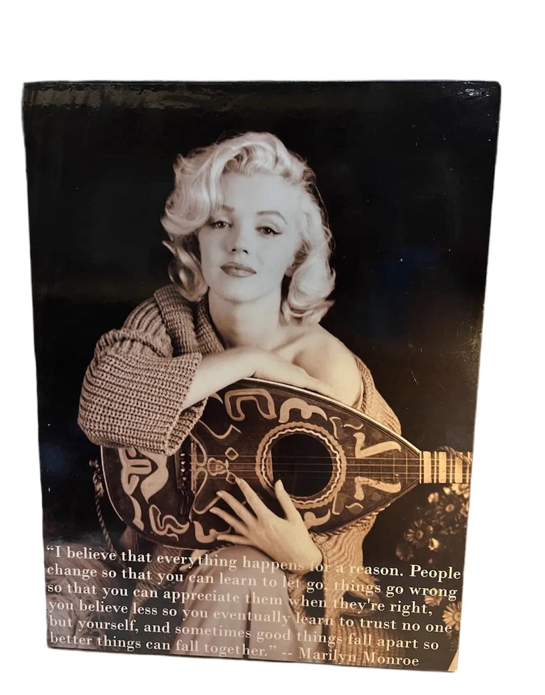 K&ouml;nnte beinhalten: Schwarz-Wei&szlig;-Fotografie von Marilyn Monroe mit einem Saiteninstrument. Sie tr&auml;gt einen strukturierten Pullover. Das Bild enth&auml;lt ein Zitat von Marilyn Monroe.