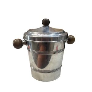 May include: A silver ice bucket with a lid and two side handles, and a top handle. The bucket has horizontal etched lines around the body and wooden ball handles. The lid also has a wooden ball handle.