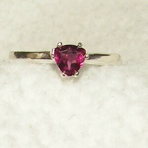 May include: A silver ring with a triangular pink gemstone.