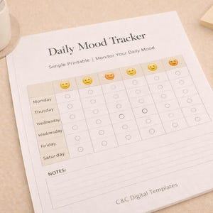Puede incluir: Una hoja impresa "Daily Mood Tracker" con una cuadrícula para rastrear los estados de ánimo diarios, con iconos de caras sonrientes. La hoja incluye secciones para cada día de la semana y una sección de notas. Un lápiz de madera y un pequeño bloc de notas también están presentes.