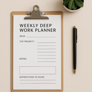 以下が含まれることがあります： 「WEEKLY DEEP WORK PLANNER」と書かれた白い紙が入ったクリップボード。 金色のペン先が付いた黒いペンがクリップボードの横にあります。 緑の葉が付いた小さな鉢植えも画像にあります。