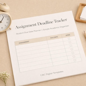 Puede incluir: Un despertador color crema, una bandeja de madera con papel, un lápiz y un bloc de notas con el texto "Assignment Deadline Tracker" están dispuestos sobre una superficie beige. El bloc de notas es un planificador de fechas de entrega para estudiantes.