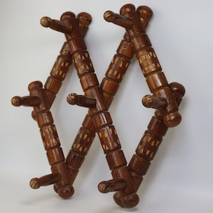 Könnte beinhalten: Zwei hölzerne Kleiderhaken mit mehreren Haken. Die Kleiderhaken sind aus dunkelbraunem Holz gefertigt und haben ein dekoratives Design. Jeder Haken hat eine Reihe von Haken zum Aufhängen von Gegenständen. Die Haken sind für die Wandmontage konzipiert.