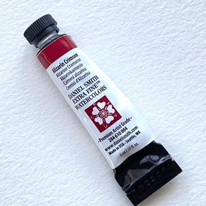 May include: A tube of Daniel Smith Extra Fine Watercolors in Alizarin Crimson. The white tube has red and black accents, with the brand name and product information printed on the front. The tube contains 5 ml of paint.
