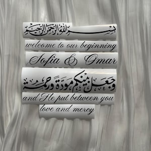 May include: White rectangular decals with black calligraphy and English text. The decals read "welcome to our beginning", "Sofia & Omar", and a quote about love and mercy. The background is a white, textured fabric.